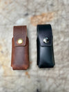 Two leather pouches, one brown and one black, on a textured surface.
