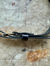 Close-up of a black leather belt with a brass buckle on a textured surface