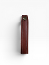 A close-up of a dark brown leather strap or loop with visible stitching and a brass snap button, shown against a plain white background.
