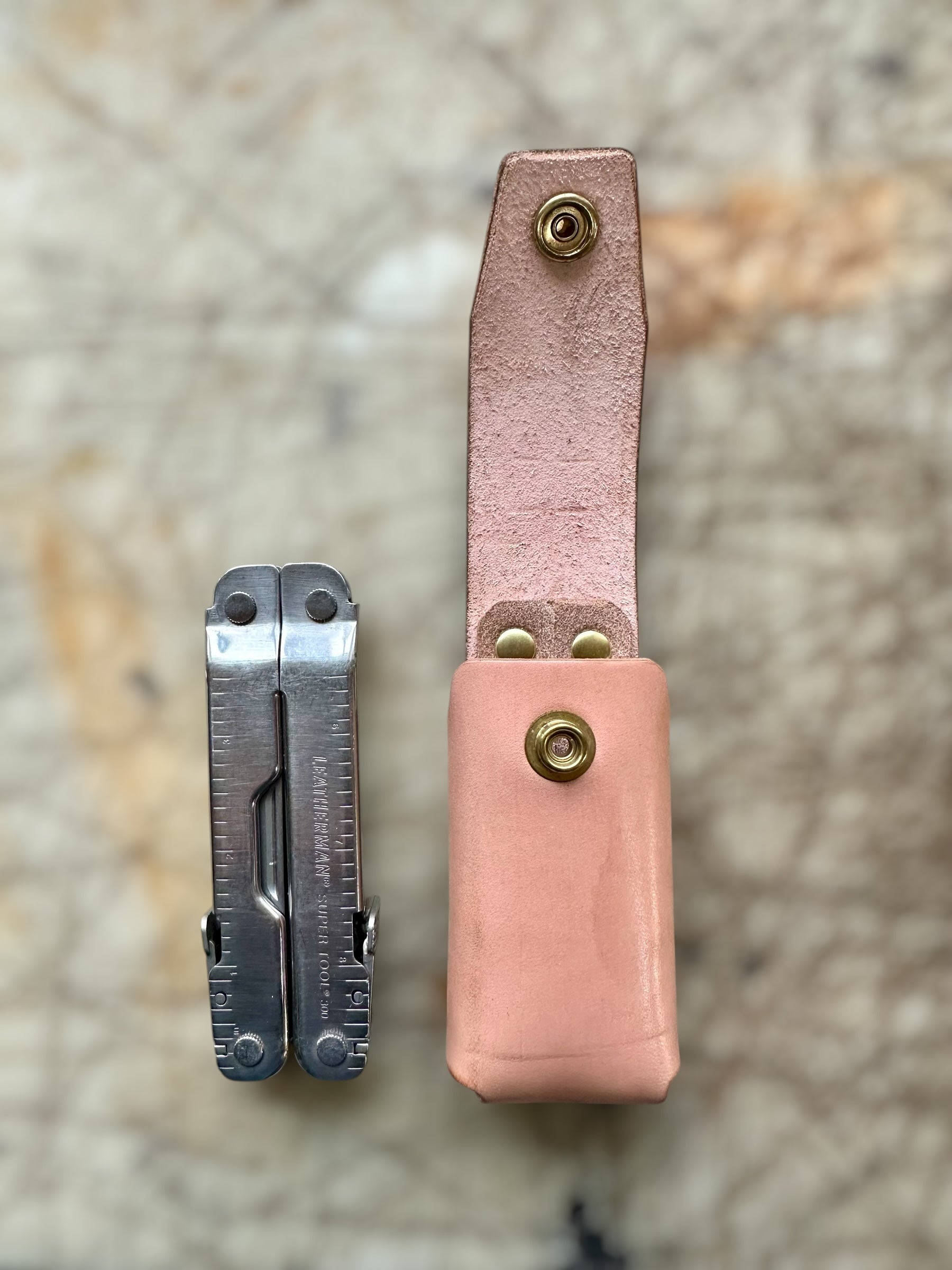 Multitool with pink leather sheath on a textured surface