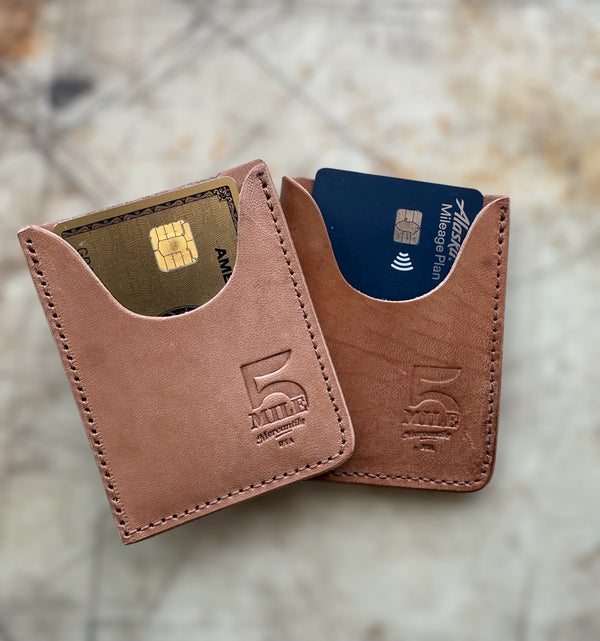 Brown leather cardholder with two cards on a blurred natural background