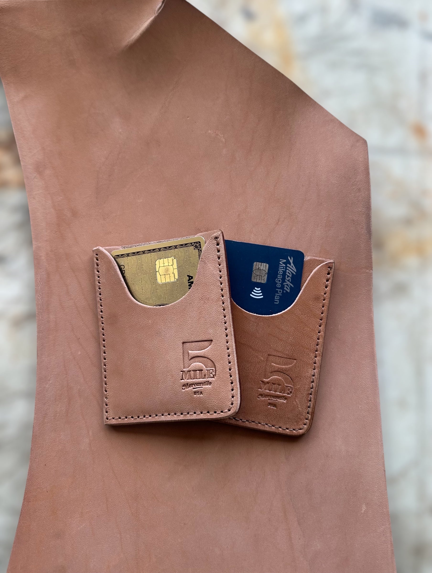 Brown leather wallet with embedded cards on a blurred natural background