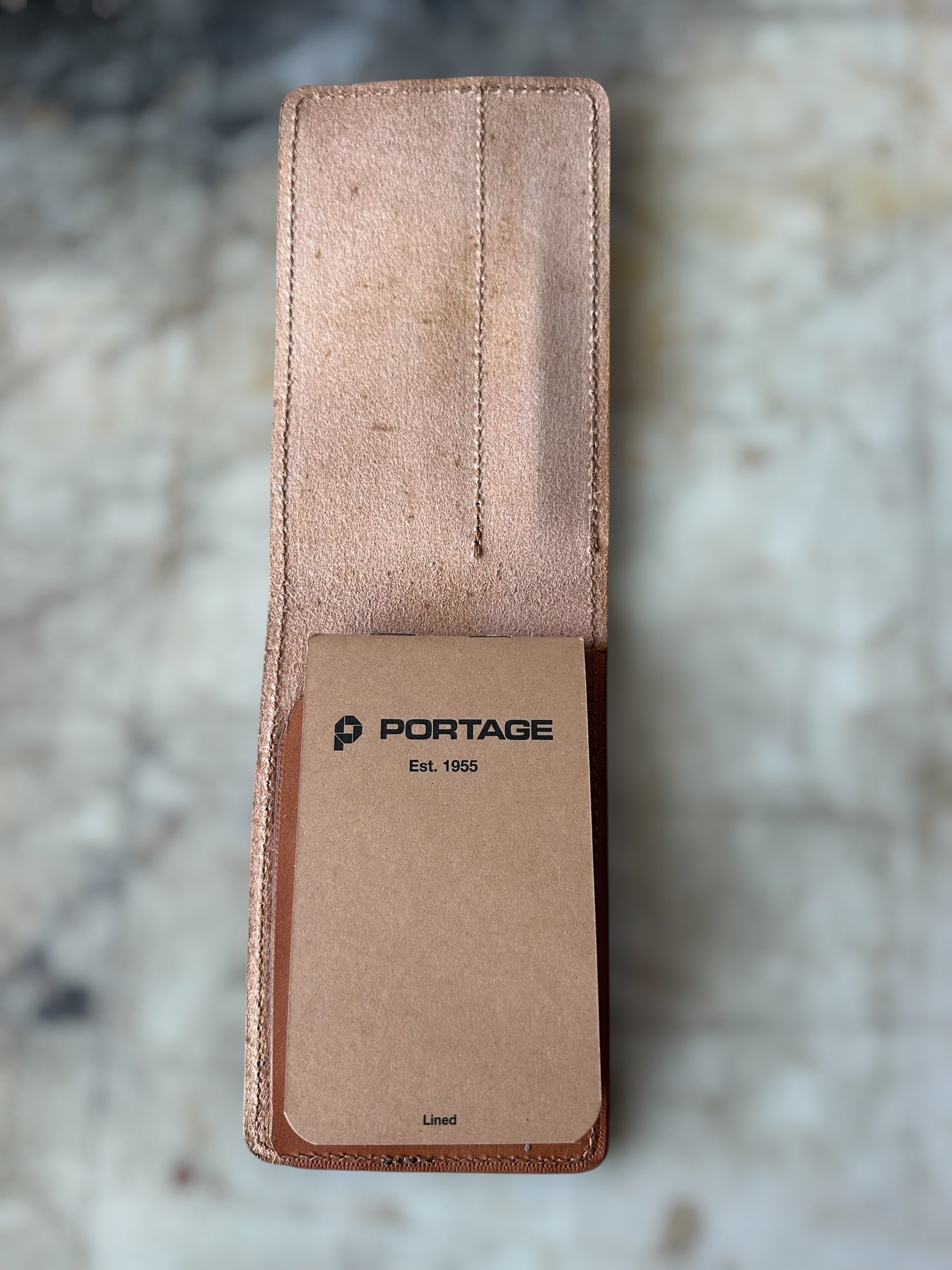 Brown leather pouch with 'Portage' branding on a marble surface