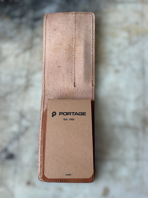 Brown leather pouch with 'Portage' branding on a marble surface