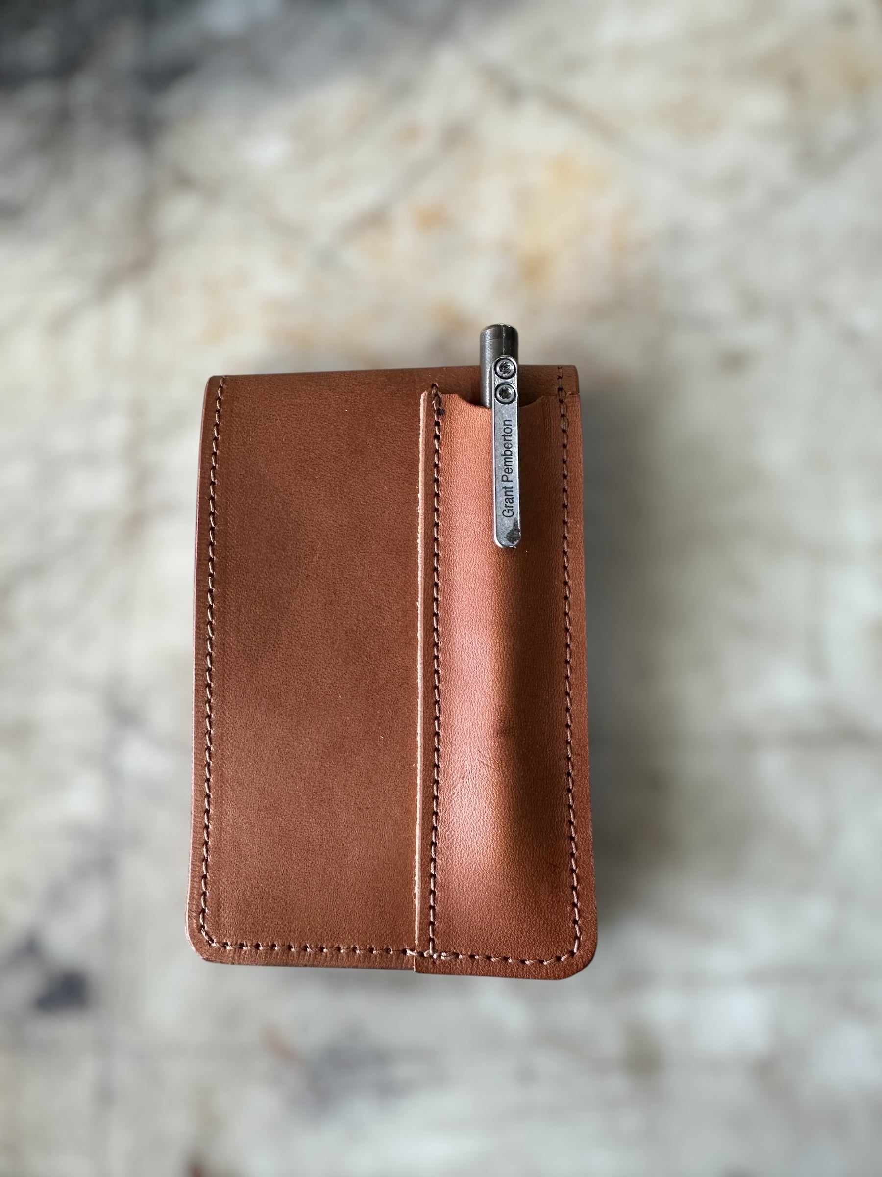 Brown leather wallet with a visible brand name on a marble surface