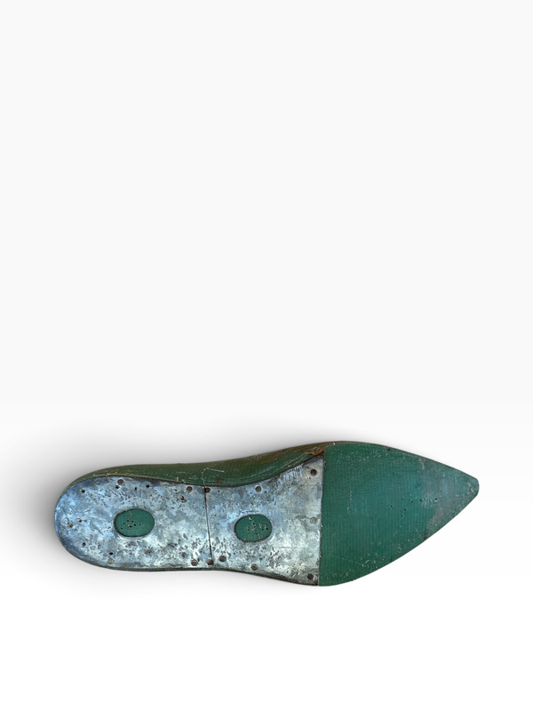 The outsole of a green pointed-toe shoe, showing a textured metallic silver-gray section with two circular green footprints and a solid dark green toe cap, photographed on a clean white background.