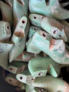 A pile of used green plastic shoe lasts, likely for leathercraft or cobblering, showing signs of wear, dirt, and handwritten markings.
