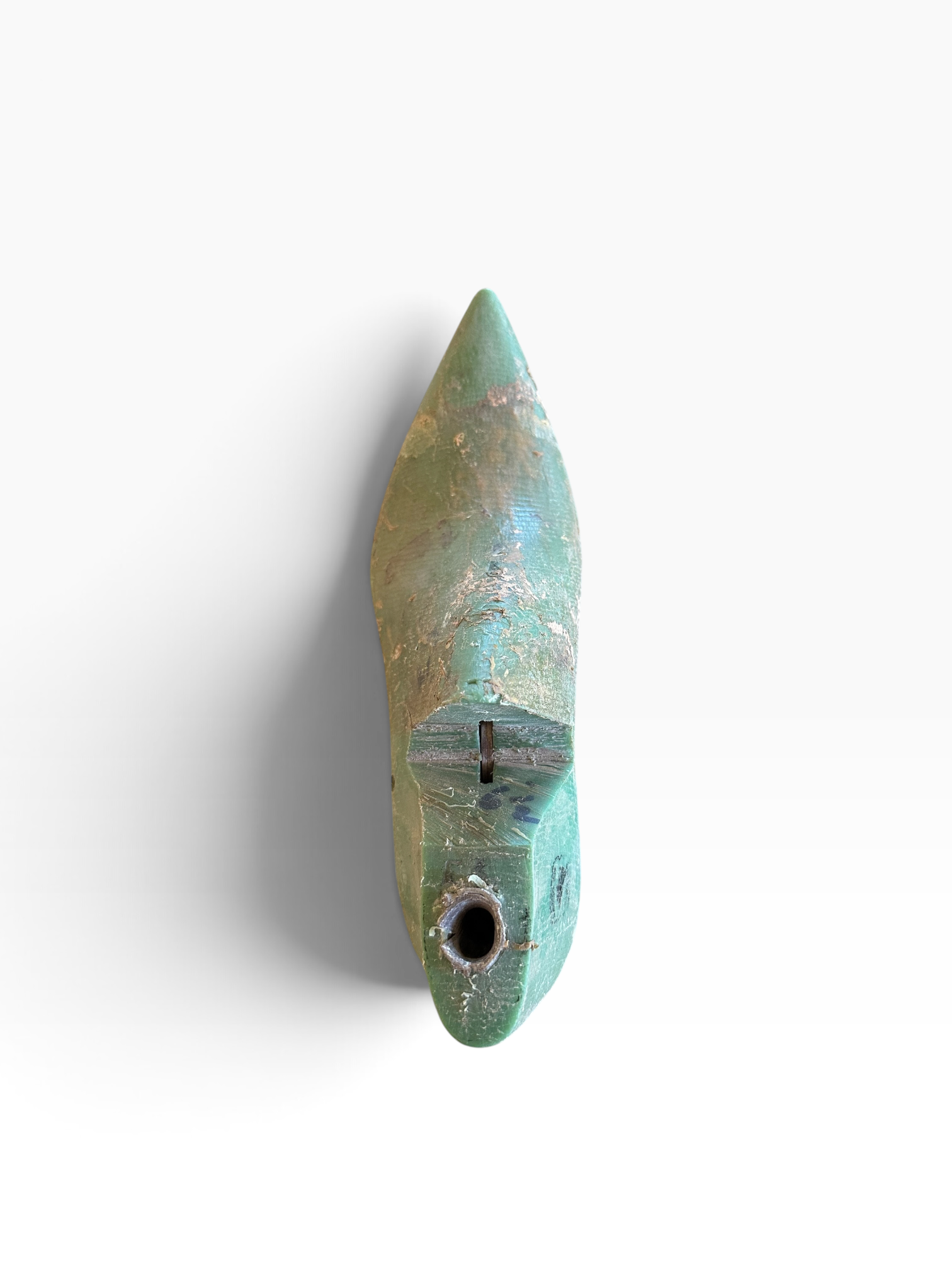 A small pointed turquoise-green object with a circular hole near the bottom, photographed against a plain white background.