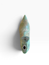 A small pointed turquoise-green object with a circular hole near the bottom, photographed against a plain white background.