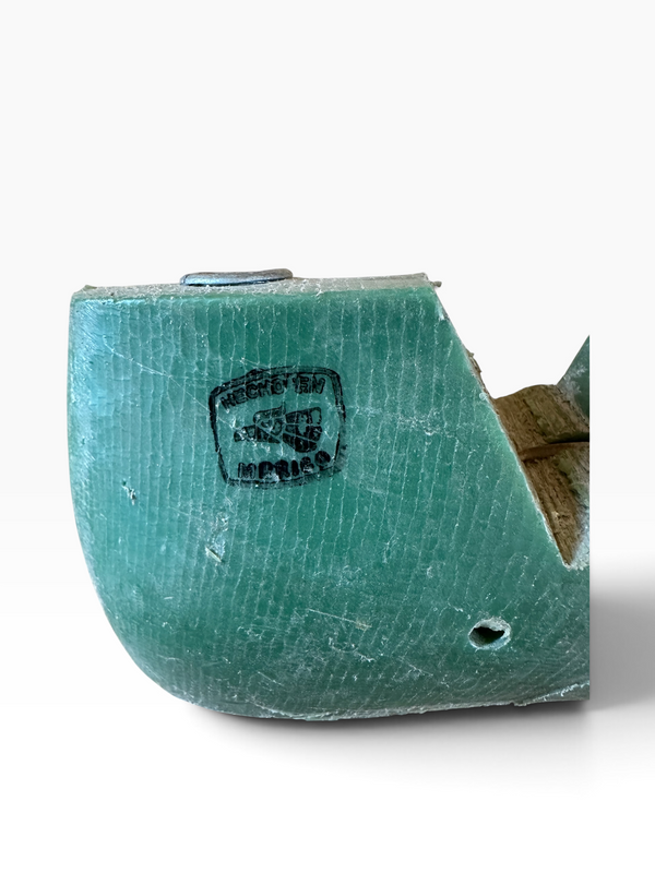 A close-up of a turquoise green textured shoe or boot sole with a stamped 'CROCHET 1935 PARIS' label, showing a brown inner lining and a small metal rivet on a white background.
