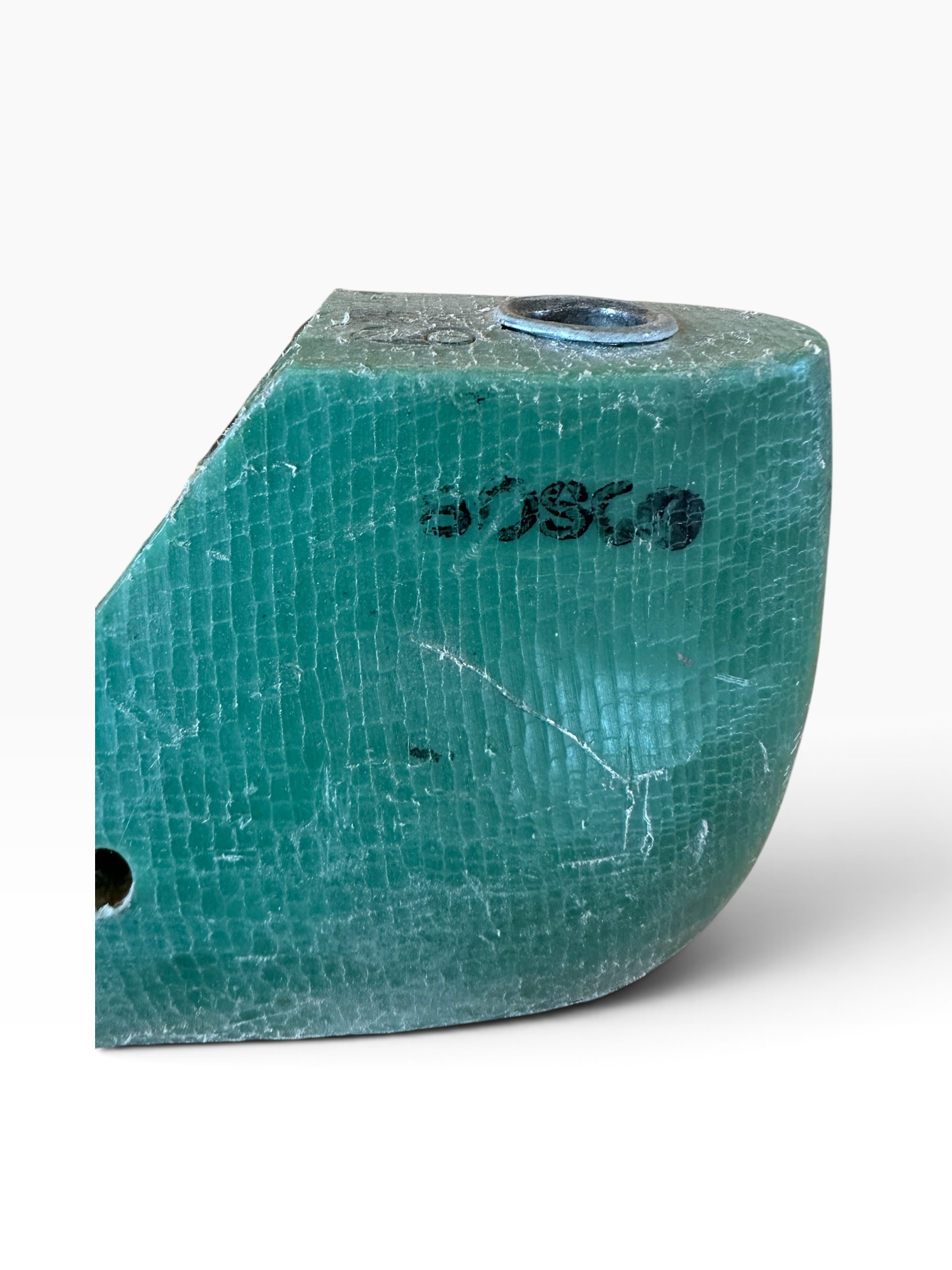 A close-up of a turquoise-green textured object with a cracked, reptile-like surface, a small circular metallic detail on top, and black printed markings, shown against a plain white background.
