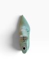 A small pointed green ceramic object with a circular hole at the base and a small metallic loop near the center, photographed against a plain white background with a soft shadow.