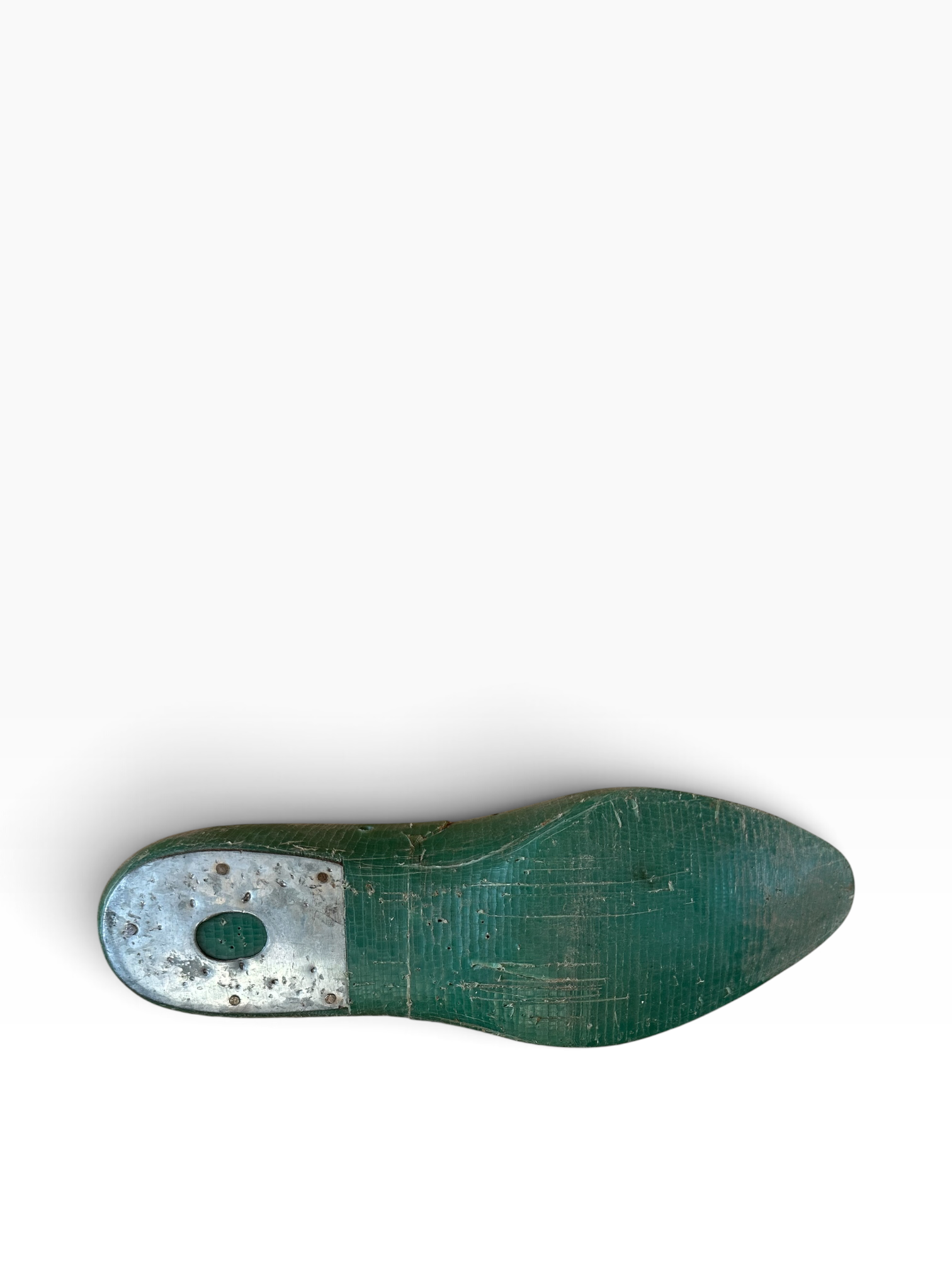 A single wooden shoe tree foot with a distressed green finish and a weathered silver metal cap on the heel, shown from a top-down view on a white background.