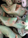 A pile of used green wooden shoe lasts with visible wear, scratches, and stamped markings.