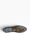The outsole of a vintage leather shoe, showing a weathered patina with blue-green verdigris on the heel and a dark brown rusted surface on the toe, photographed on a clean white background.