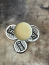 Four round metal tins of leather balm stacked