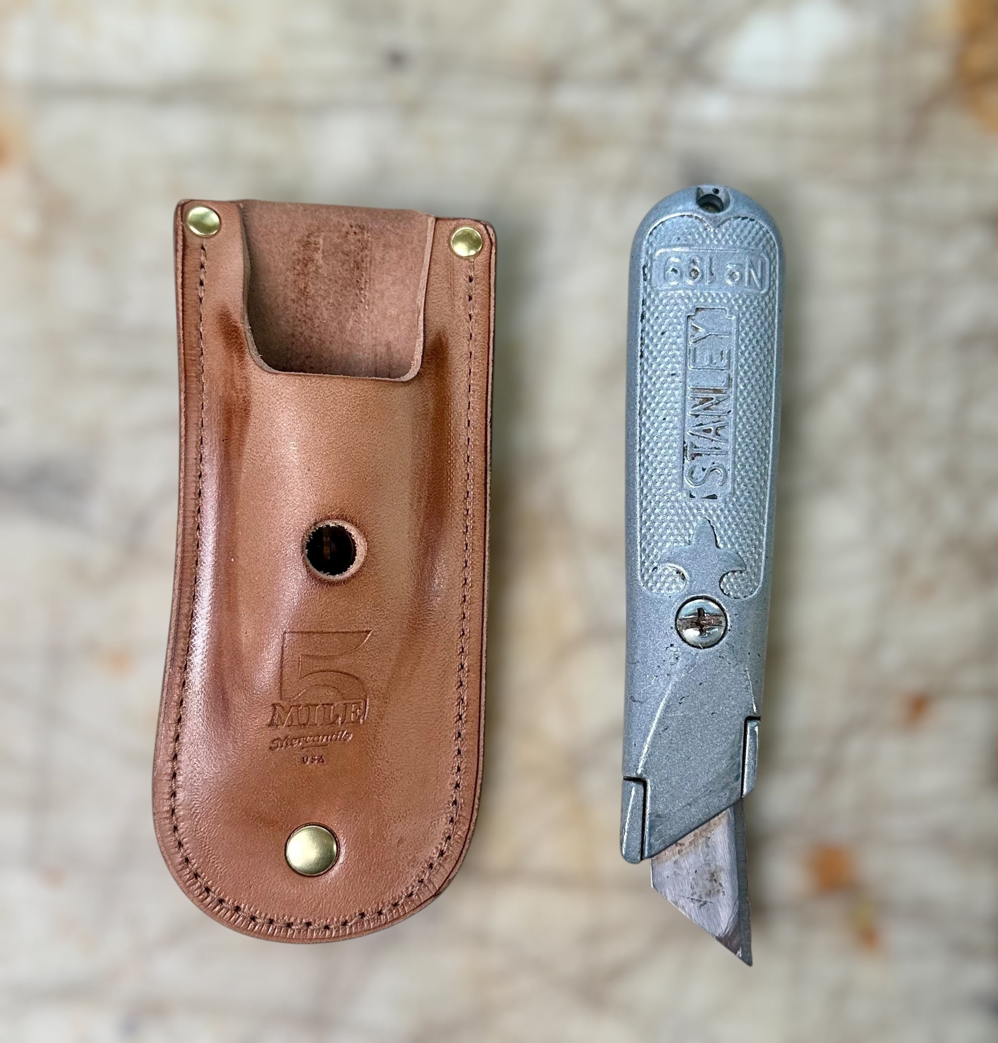 Knife with leather sheath on a textured surface