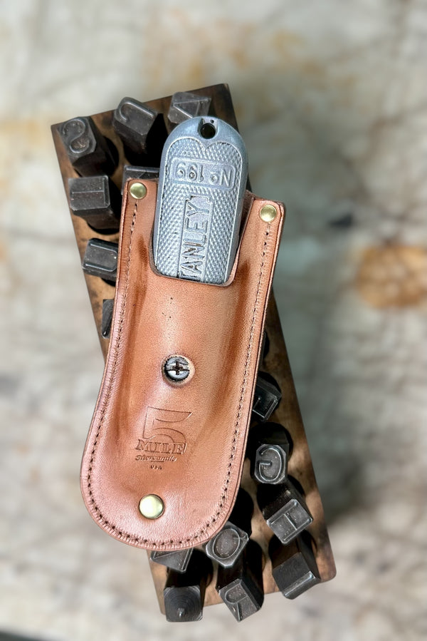 Leather knife sheath with a metal clip on a stone surface