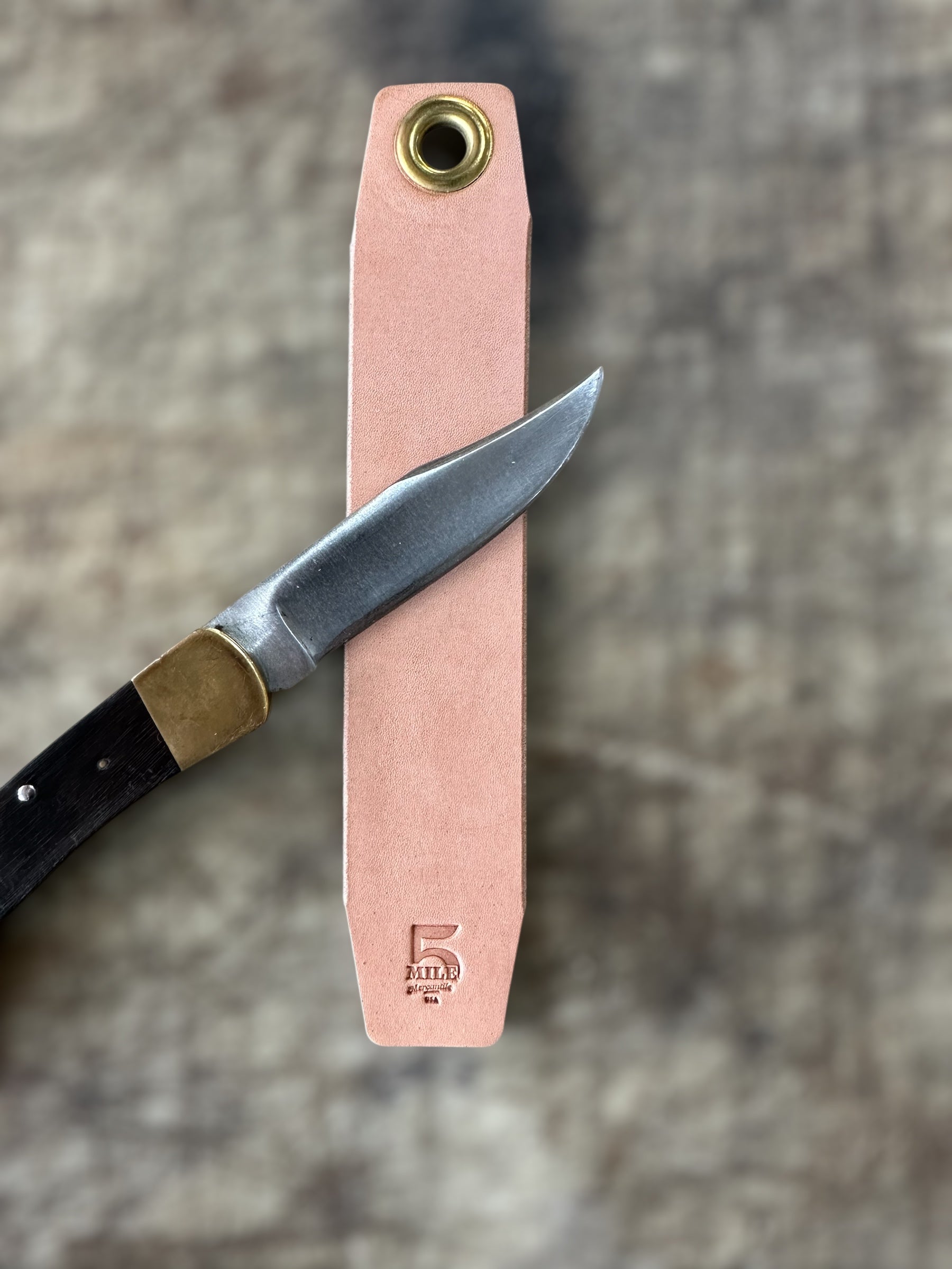 Knife with a pink sheath on a textured surface