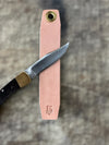 Knife with a pink sheath on a textured surface