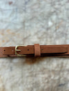 Brown leather belt with a gold buckle on a marble surface
