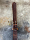 Brown leather belt with gold buckle on a textured stone background