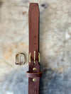 Brown leather belt with brass buckle on a textured stone background