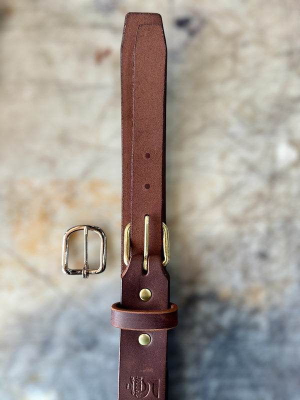 Brown leather belt with brass buckle on a textured stone background