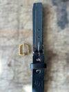 Black leather belt with gold buckle on a textured surface