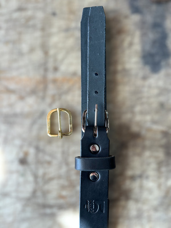 Black leather belt with gold buckle on a textured surface