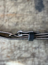 Close-up of a leather strap with a metal buckle on a textured surface
