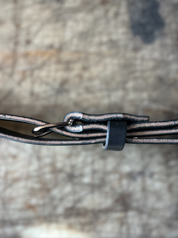 Close-up of a leather strap with a metal buckle on a textured surface