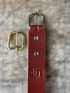 Brown leather belt with gold buckle on a textured surface