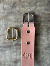 Natural colored leather belt with gold and silver buckles on a textured surface