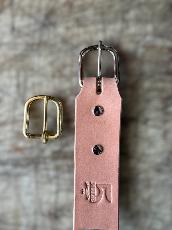 Natural colored leather belt with gold and silver buckles on a textured surface