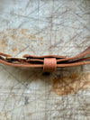 Close-up of a brown leather belt with a brass buckle on a textured surface