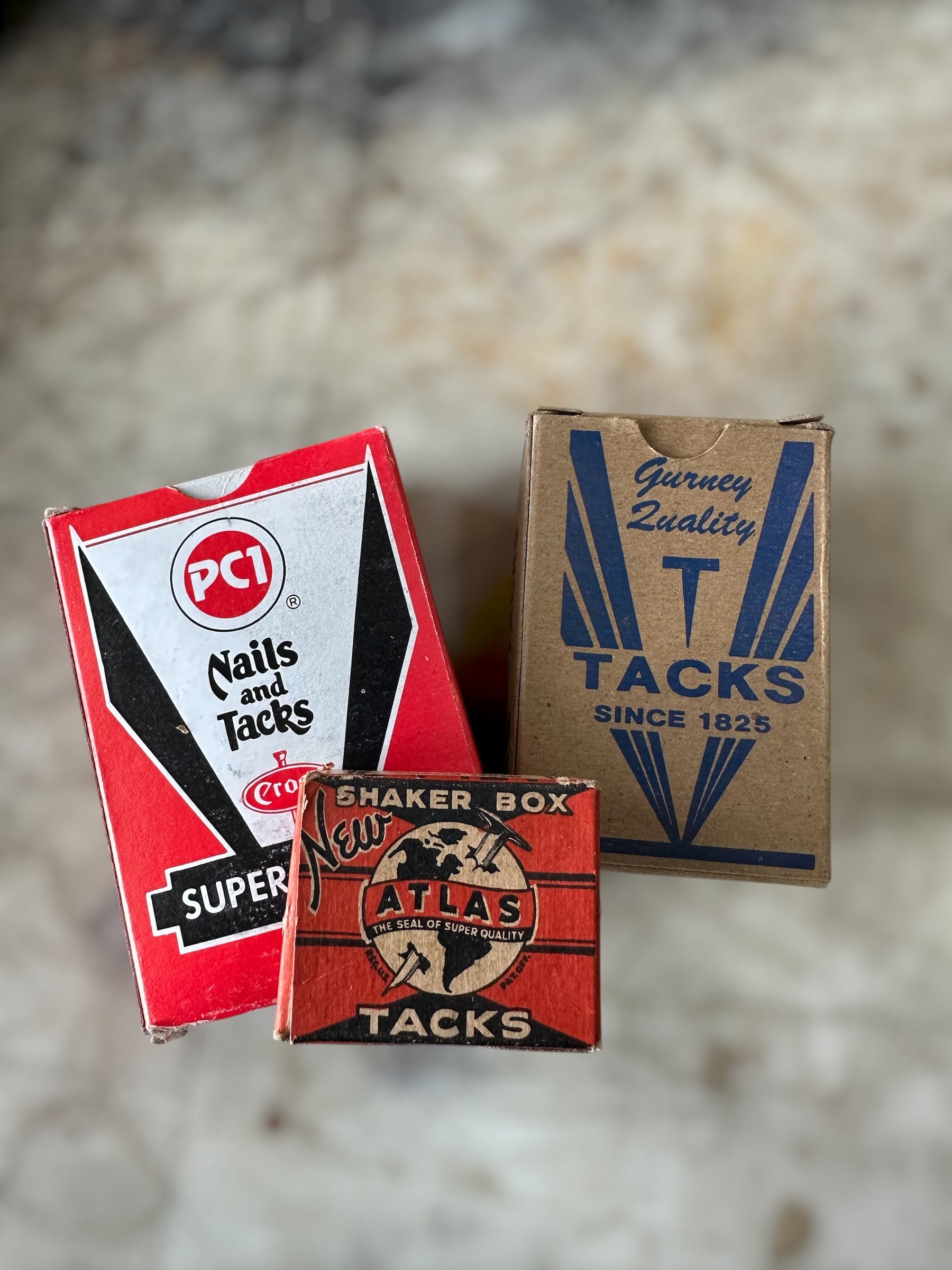 Three vintage tack boxes with different brands on a textured surface